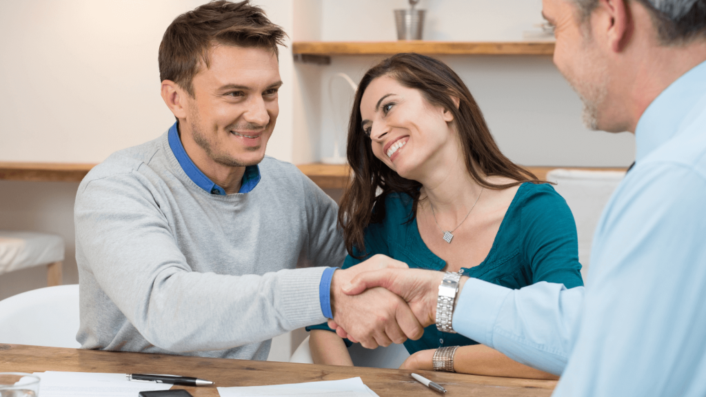 married couple shaking hands with other man about contract