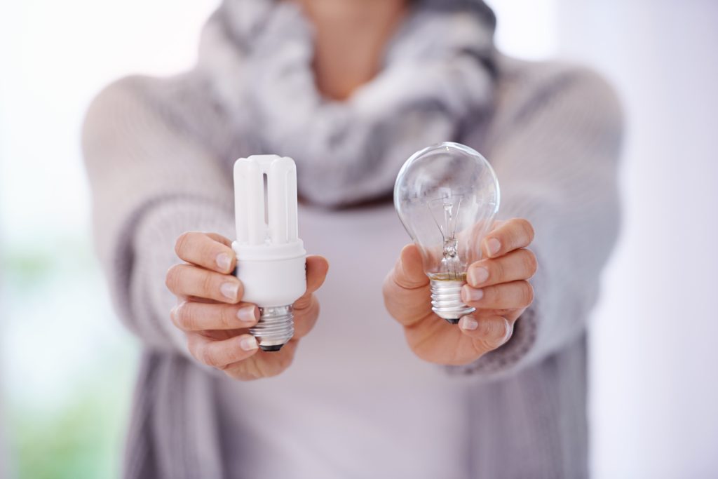Keep the lights burning longer. A cropped image of a woman holding two different lightbulbs